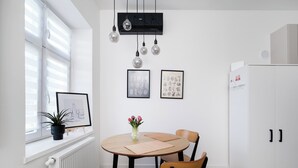 A modern kitchen with a round table, two chairs, a potted plant, and wall-mounted air conditioning. - Skierniewicka Charm Studio (Łódź)