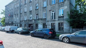 A multi-story building with a row of parked cars on the street. - Skierniewicka Charm Studio (Łódź)