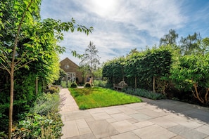 A garden with a paved pathway, a lawn, and a building with a triangular roof. - Luxury stay in the Cambridge City Centre - Flat 5 - Pass the Keys (Cambridge)