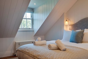 A bedroom with a sloped ceiling, a bed with rolled towels, a window with a view, and a wall-mounted light fixture. - Luxury stay in the Cambridge City Centre - Flat 5 - Pass the Keys (Cambridge)