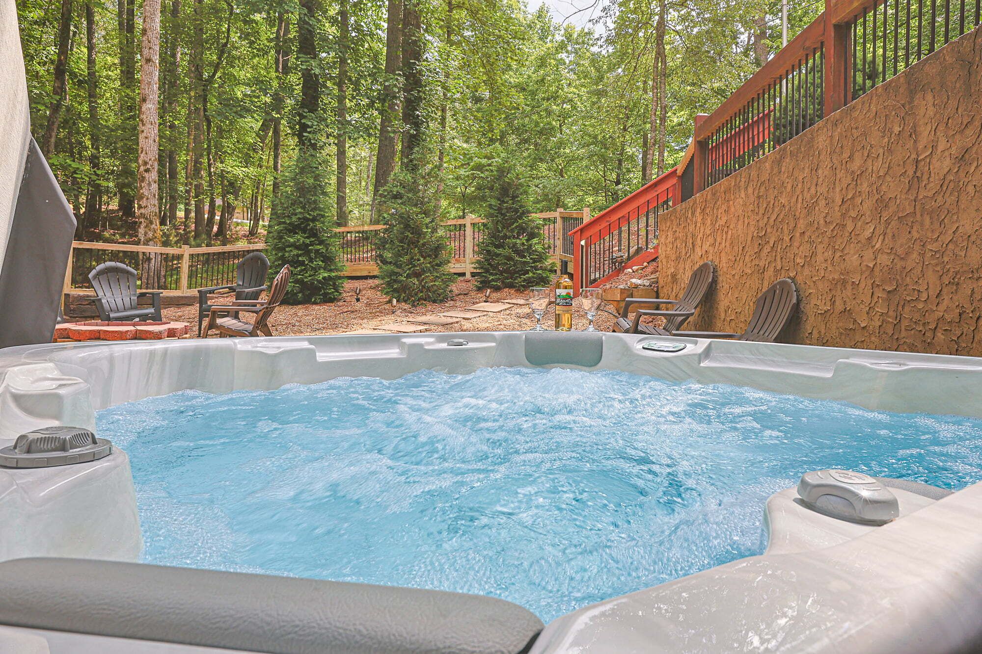 A hot tub surrounded by a wooden deck, with chairs and a small table.
