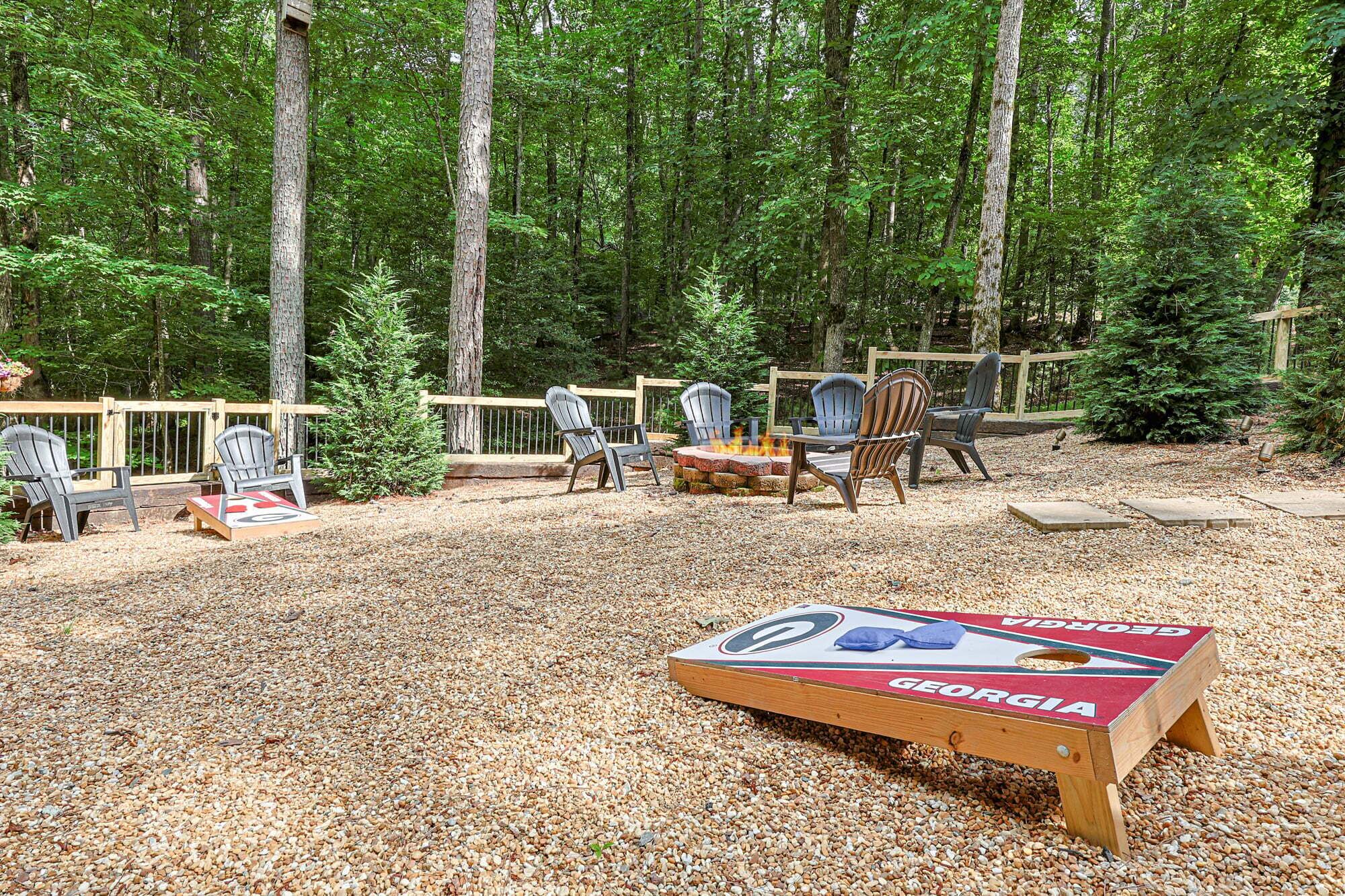 An outdoor seating area with Adirondack chairs, a fire pit, and a Georgia-themed board game.