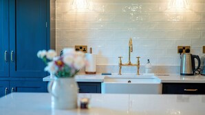 Eine moderne Küche mit weißer Arbeitsplatte, einem goldenen Wasserhahn und einer Vase mit Blumen.