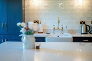 Eine moderne Küche mit weißer Arbeitsplatte, einem goldenen Wasserhahn und einer Vase mit Blumen.