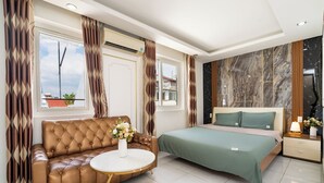 Ein modernes Schlafzimmer mit einer Ledersofa, einem runden Tisch, einem Bett mit grüner Bettwäsche und einer Marmorwand.