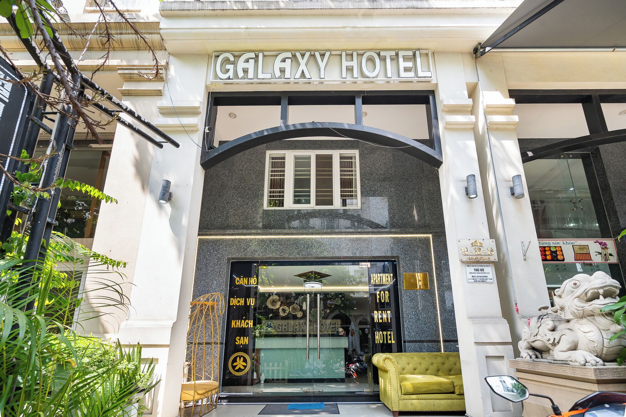 La entrada al Hotel Galaxy, con un letrero grande, una puerta de vidrio y una estatua de león.