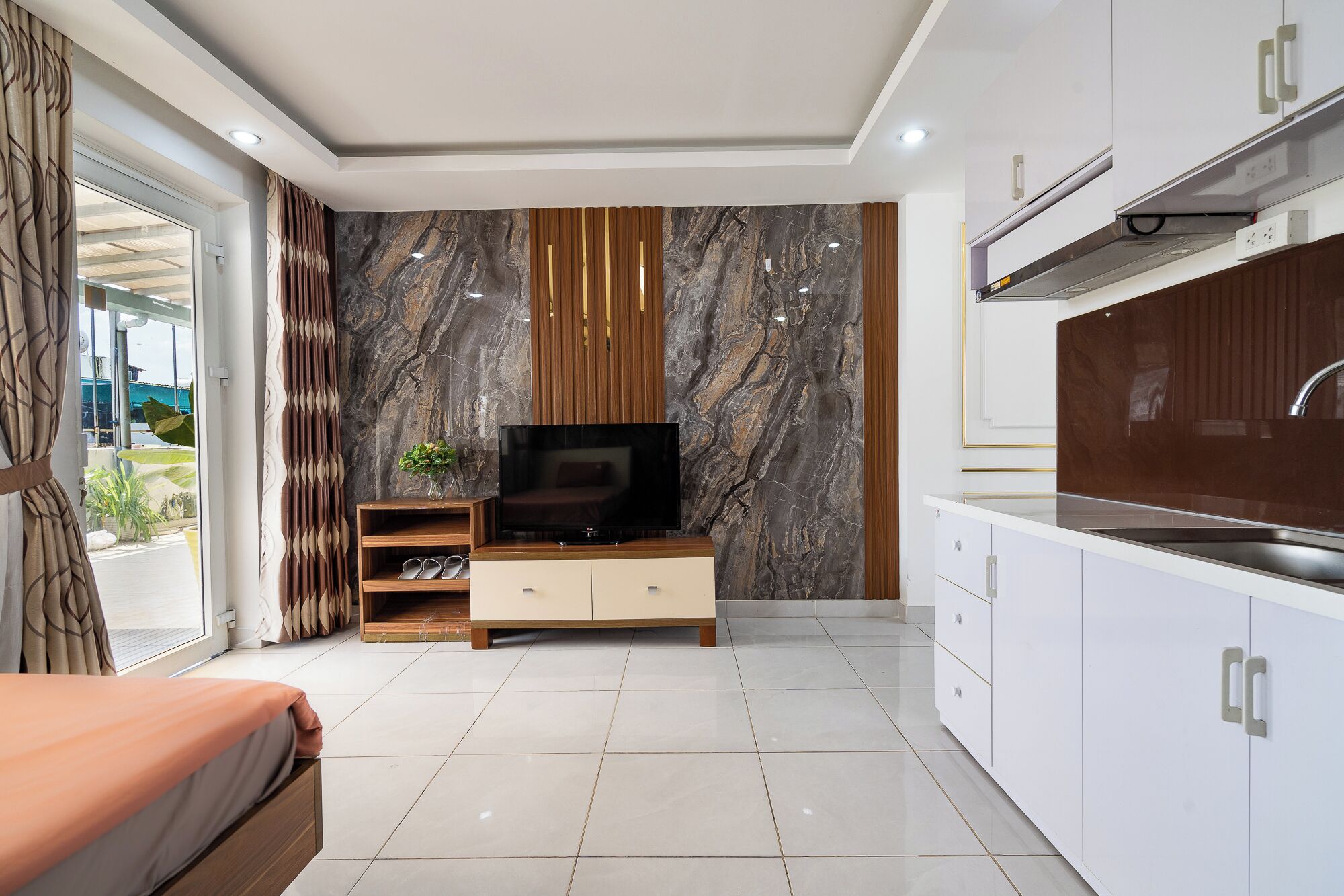 Una habitación de hotel moderna con televisión, zona de comedor y balcón con vistas.