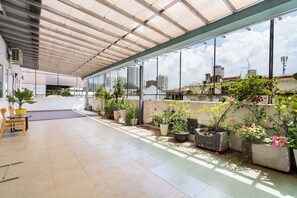 A covered outdoor area with potted plants, a wooden bench, and a view of the cityscape. - Galaxy Hotel & Apartment Near SECC (Tan Hung)