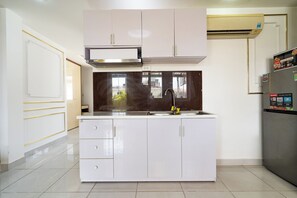 A modern kitchen with white cabinetry, a stainless steel range hood, a built-in sink, and a refrigerator with a digital display. - Galaxy Hotel & Apartment Near SECC (Tan Hung)