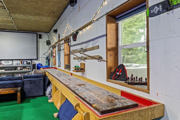 A bar area with a wooden counter, a bench, and a window with a view of trees.