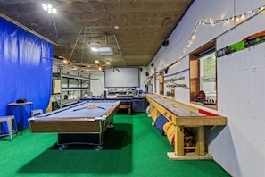 A pool table in a room with a blue wall, a wooden bench, and a window. - Pend Oreille Escape | Hot Tub, Game Room & Views (Sagle)