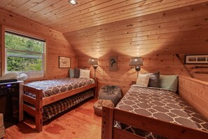 A cabin with two bunk beds, a desk, and a window with a view of trees. - Pend Oreille Escape | Hot Tub, Game Room & Views (Sagle)