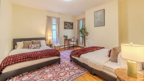 A bedroom with two beds, a desk, a chair, a lamp, and a plant. - Stylish Modern 5BR Home W/Private Balcony (Everett)