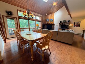 Un comedor con mesa y sillas de madera, una cocina con televisor, y un salón con sofá.