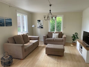 A living room with two sofas, a coffee table, a TV stand, and a chandelier.