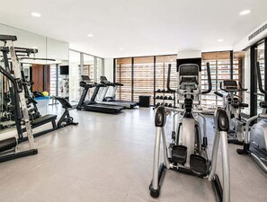 Ein Fitnessstudio mit Laufbändern, Crosstrainern und Gewichten.