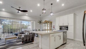 Une cuisine moderne dotée d’un îlot central, de meubles blancs et de luminaires suspendus.