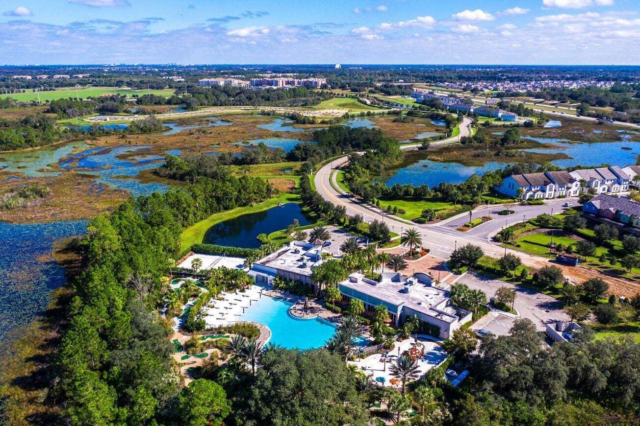 Vue aérienne d’un complexe hôtelier doté de plusieurs piscines, d’un terrain de golf et d’une vaste étendue d’eau.
