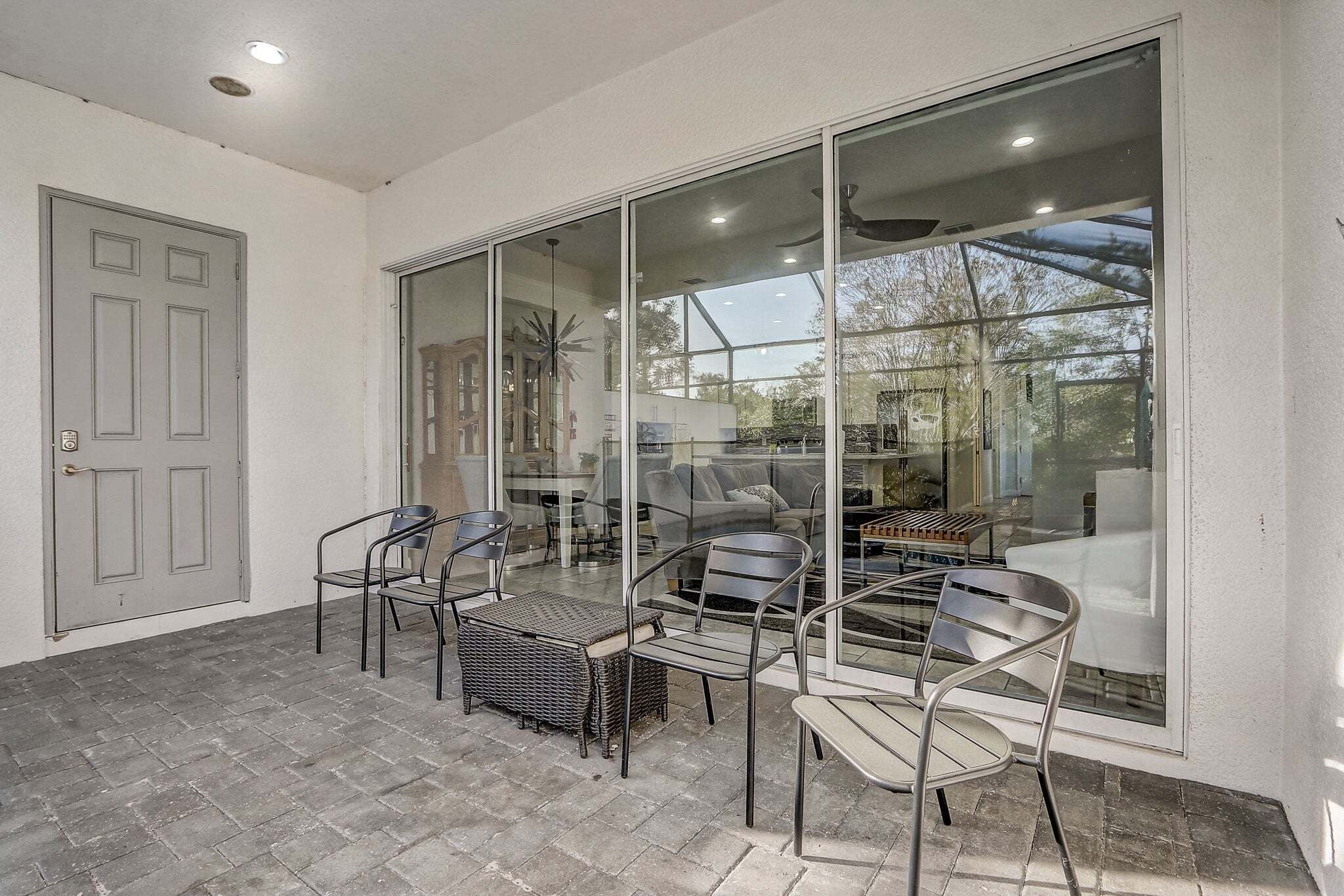 A patio with a glass door, a dining table, chairs, and a wicker chair.