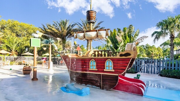 Un toboggan aquatique sur le thème des pirates, doté d’une plateforme en bois, de fenêtres et d’un drapeau.