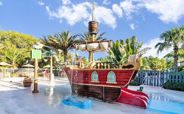 Eine wasserrutsche im Piratenschiff-Design mit Holzdeck, Fenstern und einer Flagge.