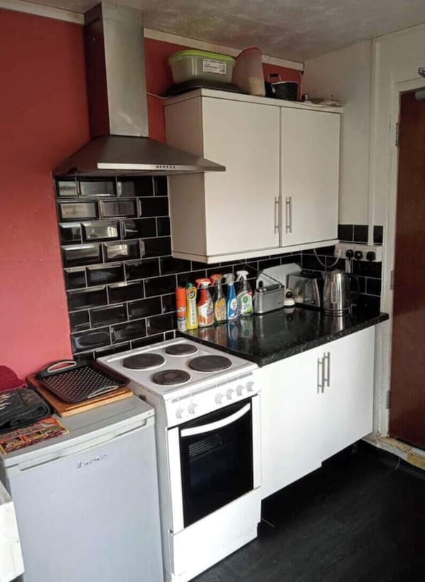 A compact kitchen with a stove, oven, and white cabinets.