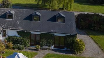 Une maison à deux étages, dotée d’un toit en pente, d’un porche à l’avant et d’un petit jardin.