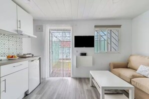A modern apartment with a kitchenette, a dining area, a TV mounted on the wall, and a sliding glass door leading to a balcony. - Tiny House in the Country (San Bartolome de Tirajana)