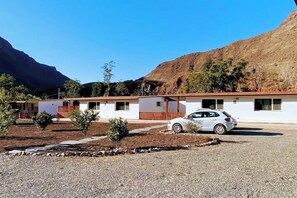 Ein Motel mit weißer Fassade, einer Schotterauffahrt und einem weißen geparkten Auto.