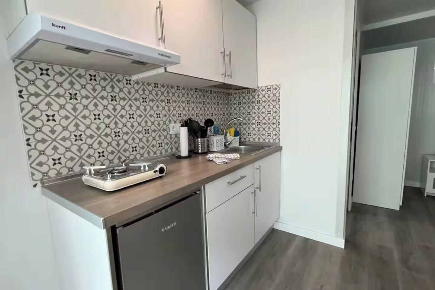 Eine moderne Küche mit weißen Schränken, einer gemusterten Spritzschutzleiste, Edelstahlgeräten und einem Geschirrspüler.