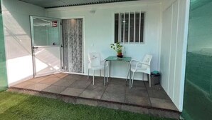 A covered patio with a sliding glass door, a small table with chairs, and a potted plant. - Renovated Tiny House (San Bartolome de Tirajana)