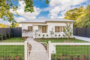 A single-story house with a front porch, a small front yard, and a gated entrance.
