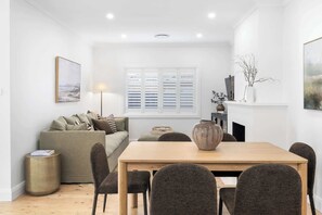 A modern living room with a sofa, dining table, chairs, a lamp, and a fireplace.