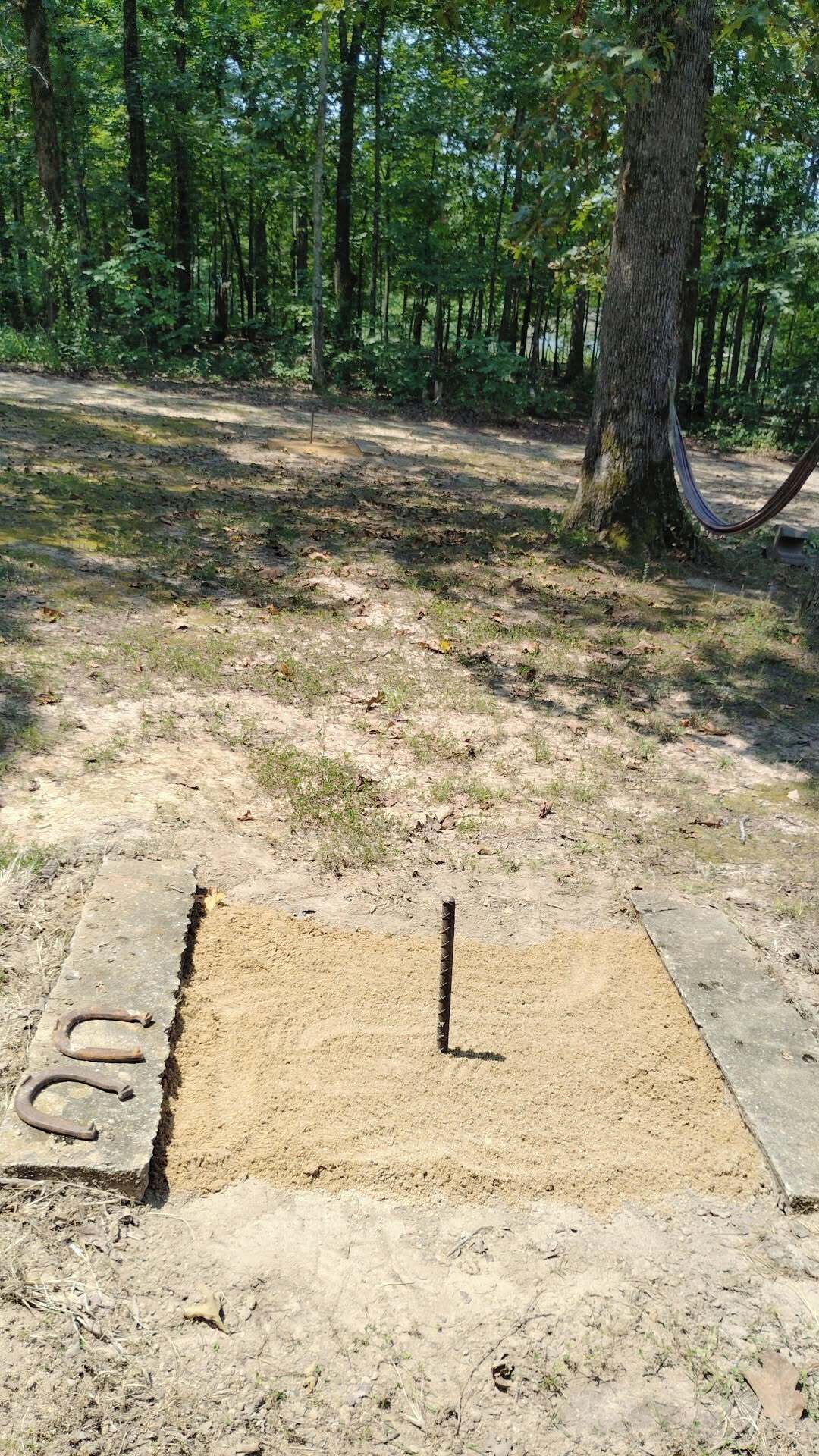 Ein sandiger Bereich mit einem Metallpfosten und einer Betonplatte mit Buchstaben.