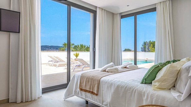 Ein Schlafzimmer mit Bett, Fernseher und Blick auf Pool und Außenbereich.