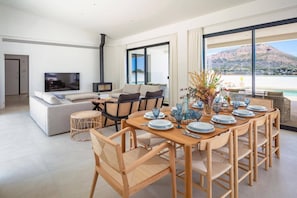 Ein modernes Wohnzimmer mit Sofa, Fernseher und Essbereich mit Stühlen und einem Tisch für sechs Personen.