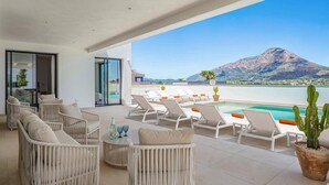 Eine Terrasse mit Liegestühlen und einem Pool mit Blick auf einen Berg und ein Gewässer.