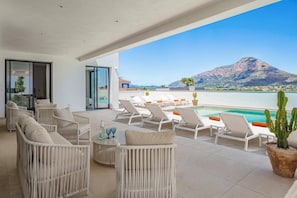 Eine Terrasse mit Liegestühlen und einem Pool mit Blick auf einen Berg und ein Gewässer.