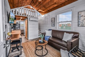 A cozy interior with a brown leather sofa, a wooden desk, and a globe. - Tiny Home Village Near Dollywood | Sleeps 60+ (Sevierville)