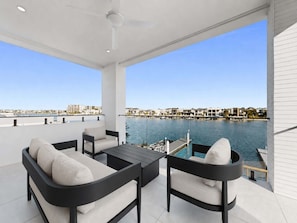 Ein Balkon mit einer Couch, einem Tisch und Stühlen mit Blick auf eine Marina.