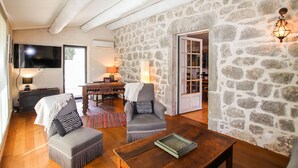 A cozy living room with a stone wall, wooden furniture, a TV, and a fireplace. - Awesome home in Labeaume with WiFi (Labeaume)