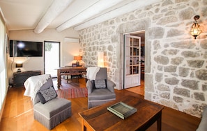 Ein gemütliches Wohnzimmer mit Steinwand, Holzmöbeln, Fernseher und Kamin.