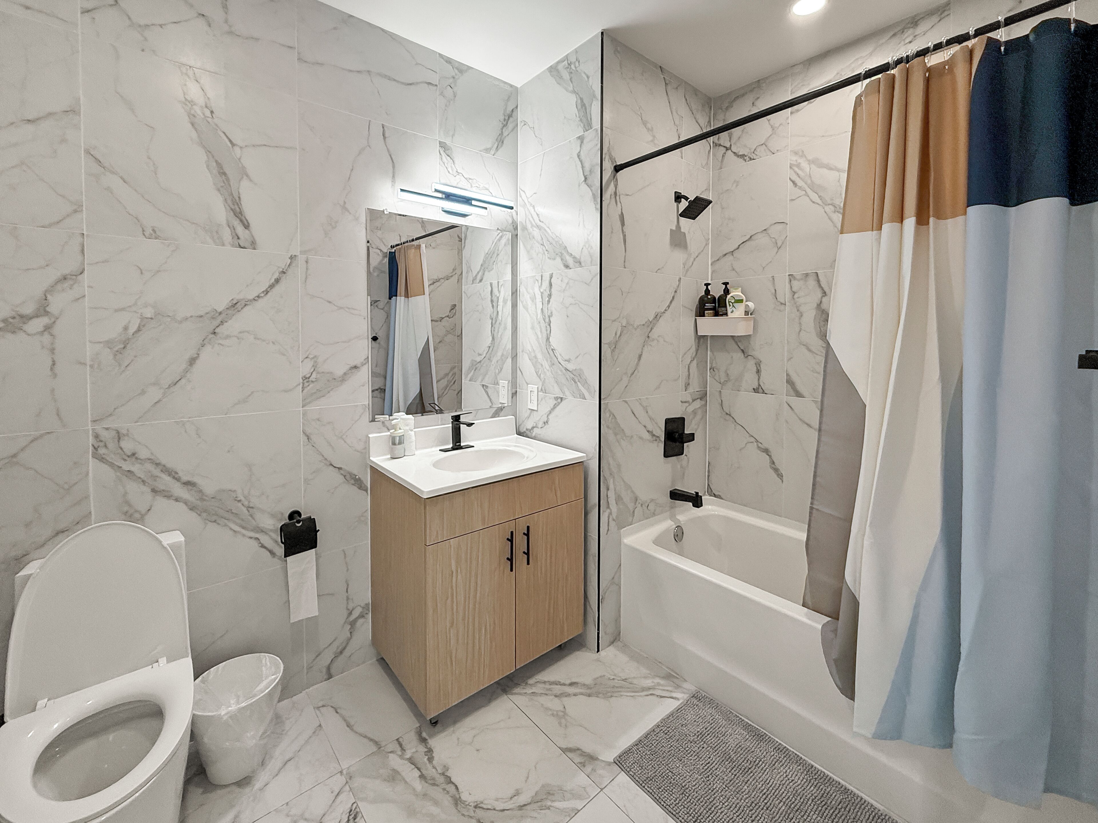 A bathroom with a toilet, sink, mirror, shower, and bathtub.