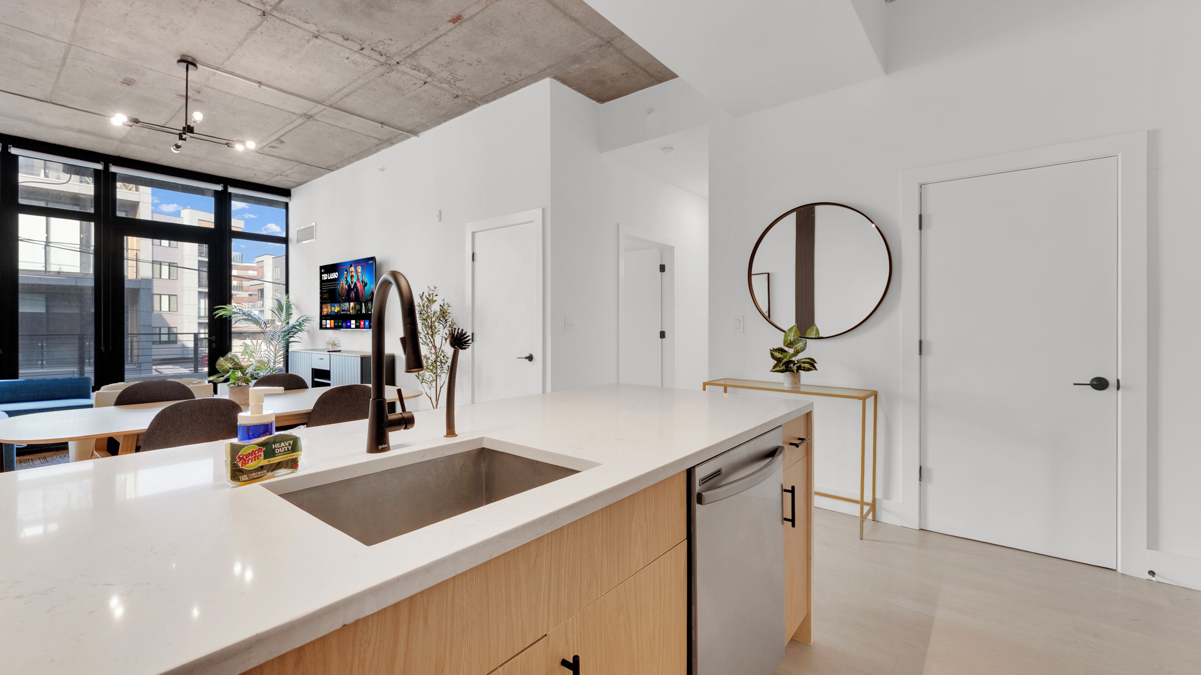 Een moderne keuken met een groot eiland, een ingebouwde vaatwasser en een eethoek met een blauwe bank.