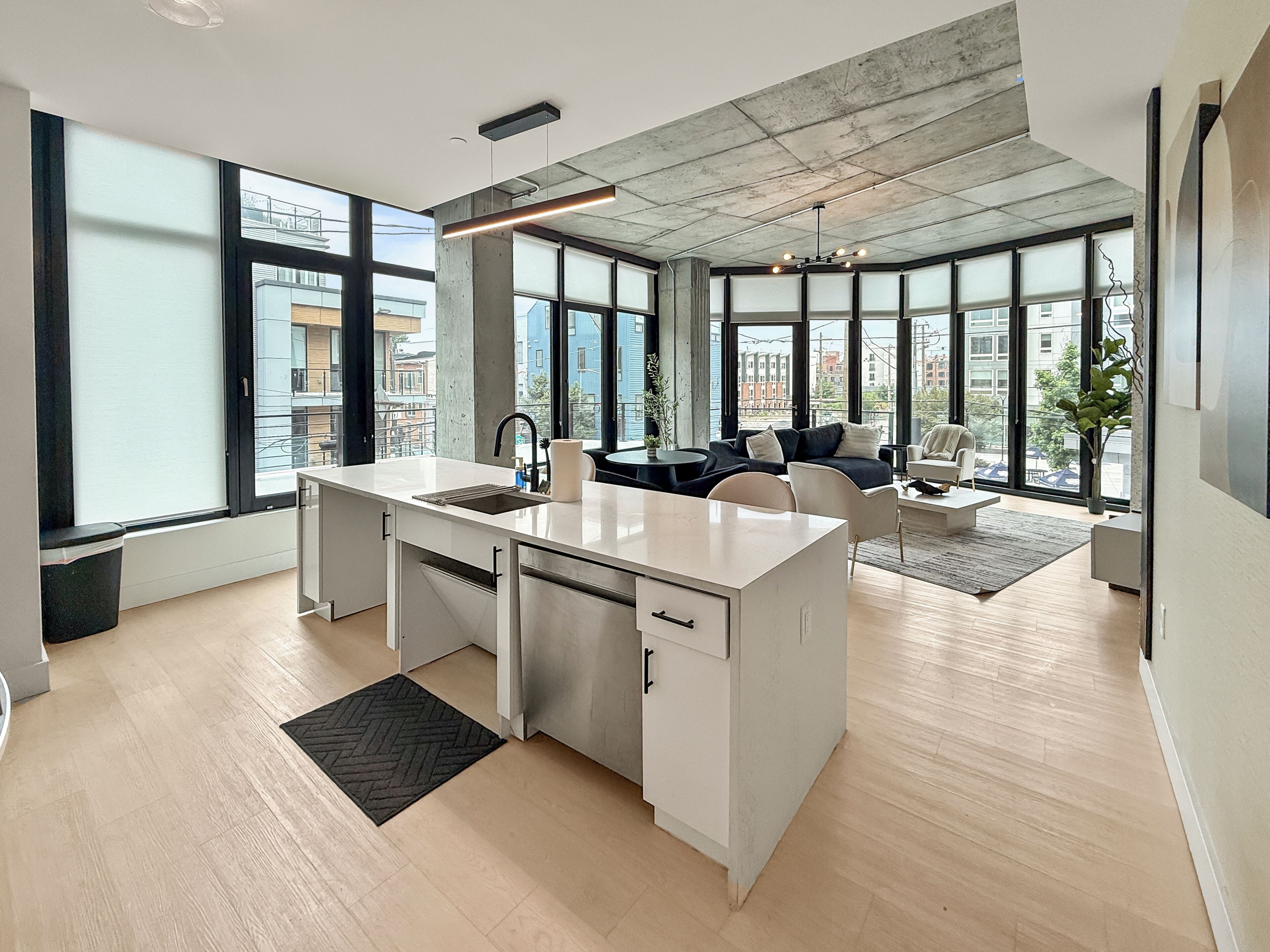 A modern kitchen with a central island, large windows, and a view of the city.