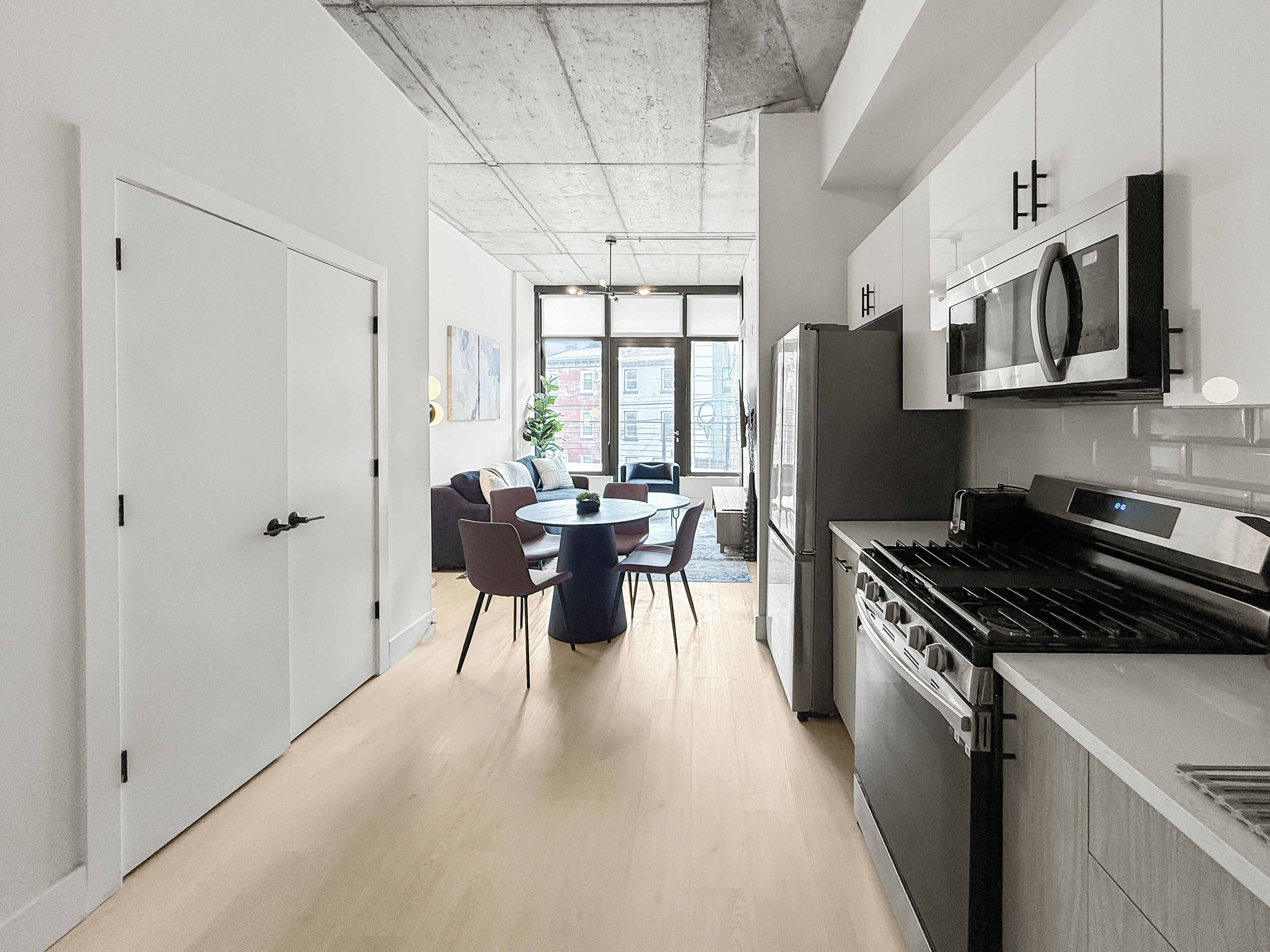 A modern kitchen with a central island, stainless steel appliances, and a dining area with chairs and a table.