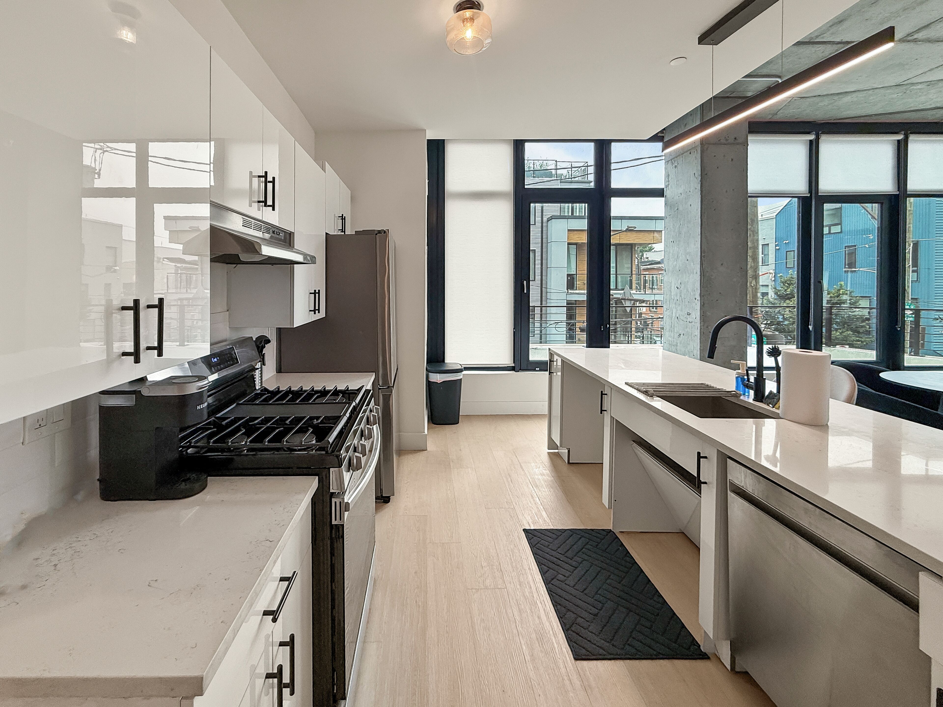 A modern kitchen with a stove, sink, and large windows.