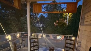 Un espacio de descanso techado al aire libre con mesa y sillas, una lámpara colgante y vistas del exterior.