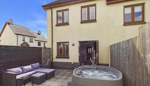 Ein Wohnhaus mit Terrasse, Sitzgelegenheiten im Freien und einem Whirlpool.