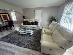 A modern living room with a sofa, coffee table, and a dining area with chairs.